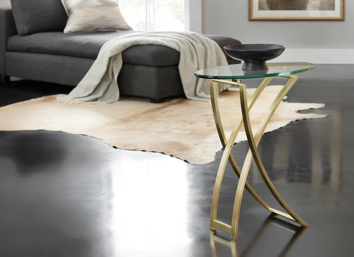 Pictured in this lifestyle photo in a satin brass finish, The Playa Side Table is an elegant blend of modern design and artistic sophistication, perfect for adding a touch of contemporary style to any room.
This metal and glass end table features an oval-shaped glass top that sits gracefully on a metal frame with subtle, flowing curves. Its sleek oil-rubbed bronze finish enhances the table's refined look, making it an ideal choice for living rooms, bedrooms, or lounge areas.