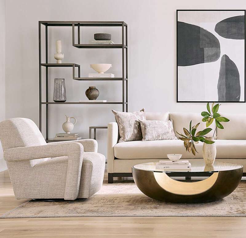 Pictured in this lifestyle photo is the Soleil cocktail by Modern Elements furniture in a bronze / gold leaf finish. The Soleil Cocktail, part of the Phoenix Collection, is an American-made resin cocktail table featuring a distinctive cut-out base design, paired with a sleek tempered glass top that enhances its modern appeal. The rounded base showcases a beautiful two-tone finish, adding depth and dimension to its sculptural form.