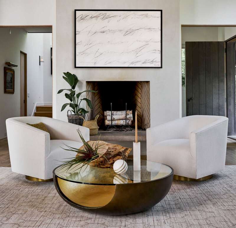 Pictured in this lifestyle photo is the Soleil Cocktail by Modern Elements Furniture in a bronze / gold leaf finish. The Soleil Cocktail, part of the Phoenix Collection, is an American-made resin cocktail table featuring a distinctive cut-out base design, paired with a sleek tempered glass top that enhances its modern appeal. The rounded base showcases a beautiful two-tone finish, adding depth and dimension to its sculptural form.