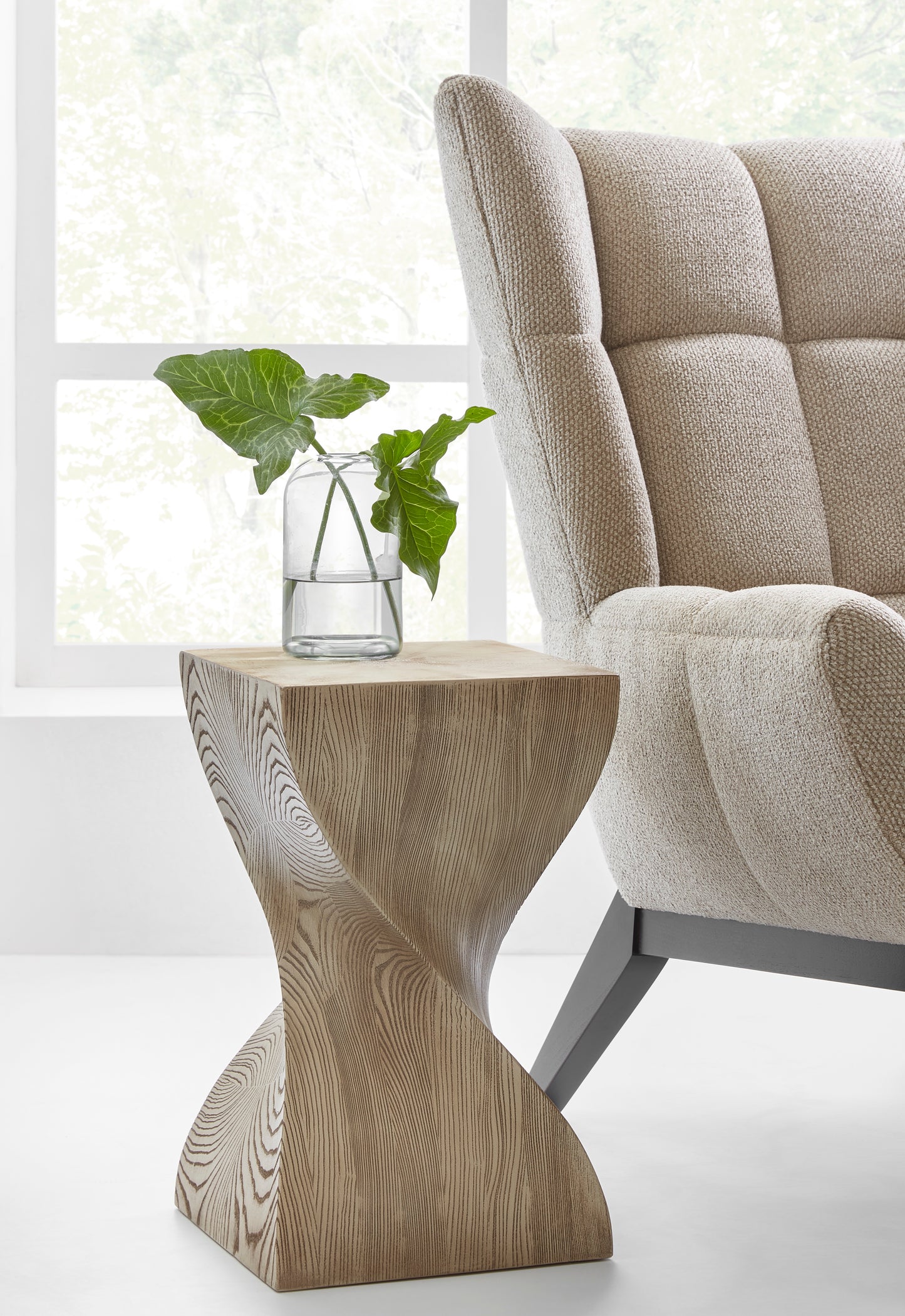 Pictured here, The Twist End Table, with a sleek design and clean lines, is a modern end table that effortlessly enhances a variety of living spaces, from contemporary living rooms to chic lounge areas.
The natural wood grain cerused oak finish adds an organic touch, blending modern design with a nod to natural elements. This versatile resin table is perfect for those looking to elevate their home decor by combining minimalist elegance with earthy, organic components.