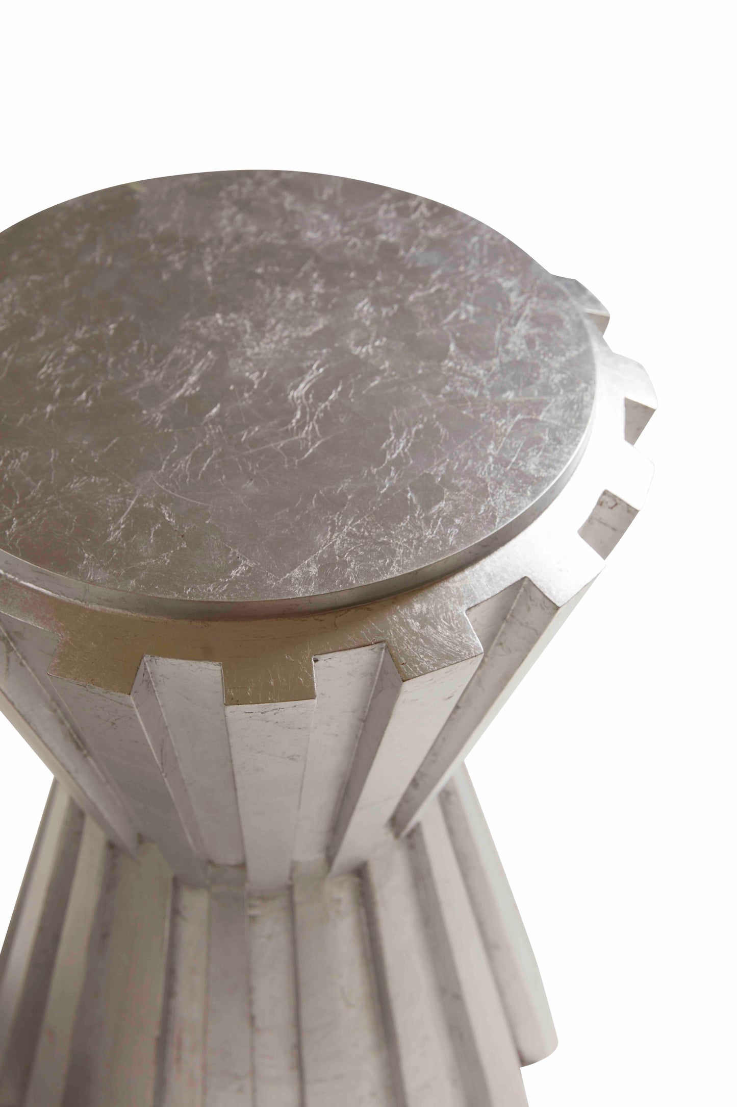 Pictured in this detail shot from an above vantage point, The Norwood Resin Accent Table is a unique American-made pull-up table that blends industrial inspiration with contemporary elegance.
Carefully crafted with the utmost quality, this table is inspired by the design of an industrial cog, modernized with a striking hand-applied Silver Leaf finish. The Norwood Spot Table serves as both a functional piece and an artistic statement, adding a touch of sophisticated style to any room.