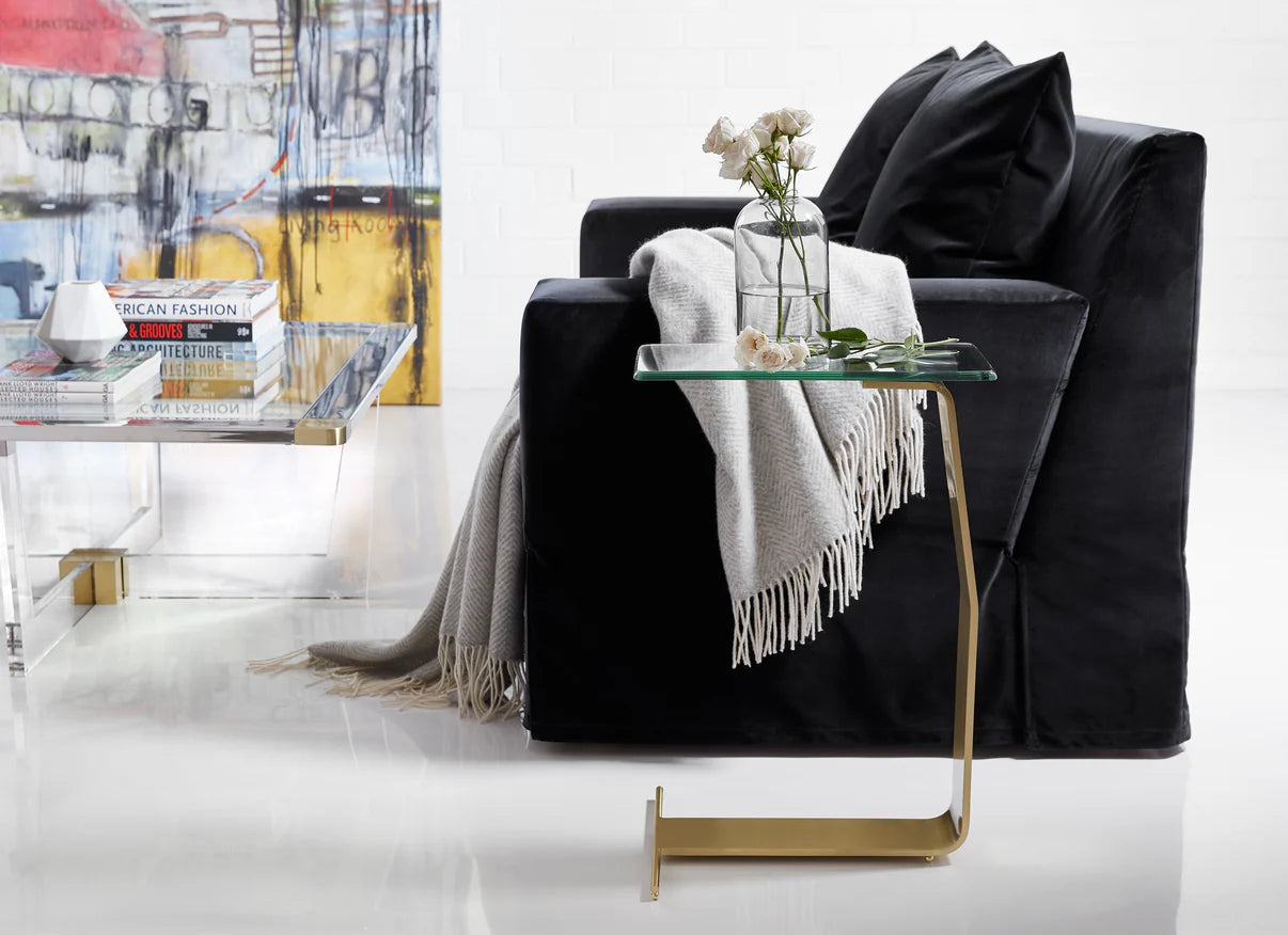 This is a lifestyle photo of the Plateau Side table shown in satin brass.

Featuring a clear glass tabletop that rests on a sleek, sculptural metal frame, this metal and gla
Featuring a clear glass tabletop that rests on a sleek, sculptural metal frame, this metal and glass side table adds a touch of sophistication to your home decor. The unique frame, crafted from a single piece of metal, creates a contemporary sculpture-like form that serves as both a functional end table and a stylish accent piece.