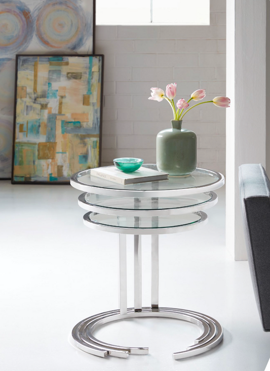 Pictured in this lifestyle shot is the Trilogy Nesting Tables by modern Elements Furniture. Each table in this stylish set features a sleek metal frame with a glass tabletop, offering a minimalist design that blends seamlessly with various interior styles. Identical in design but distinctive in size, these contemporary nesting tables can be arranged together for a layered look or used separately throughout the home for functional versatility.