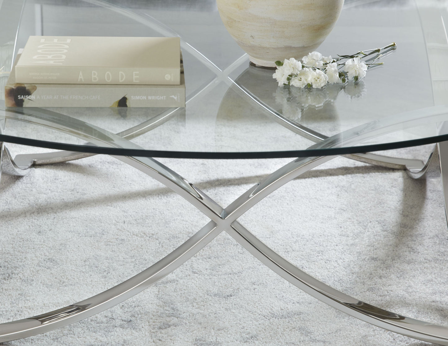 This is a detail shot of the Diana Cocktail table, showcasing its unique table base and classic glass table top. The frame is modern and futuristic, and its design exudes unique contemporary furnishing.