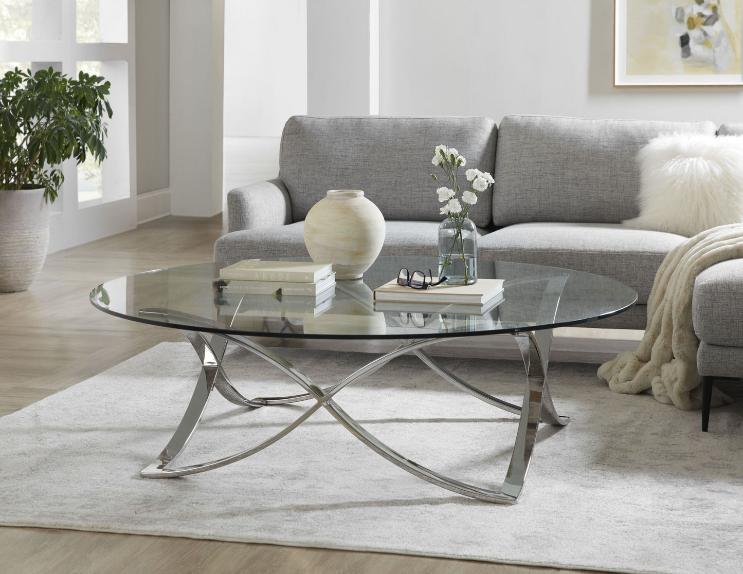 This is a lifestyle shot of the Diana Cocktail table, showcasing its unique table base and classic glass table top.