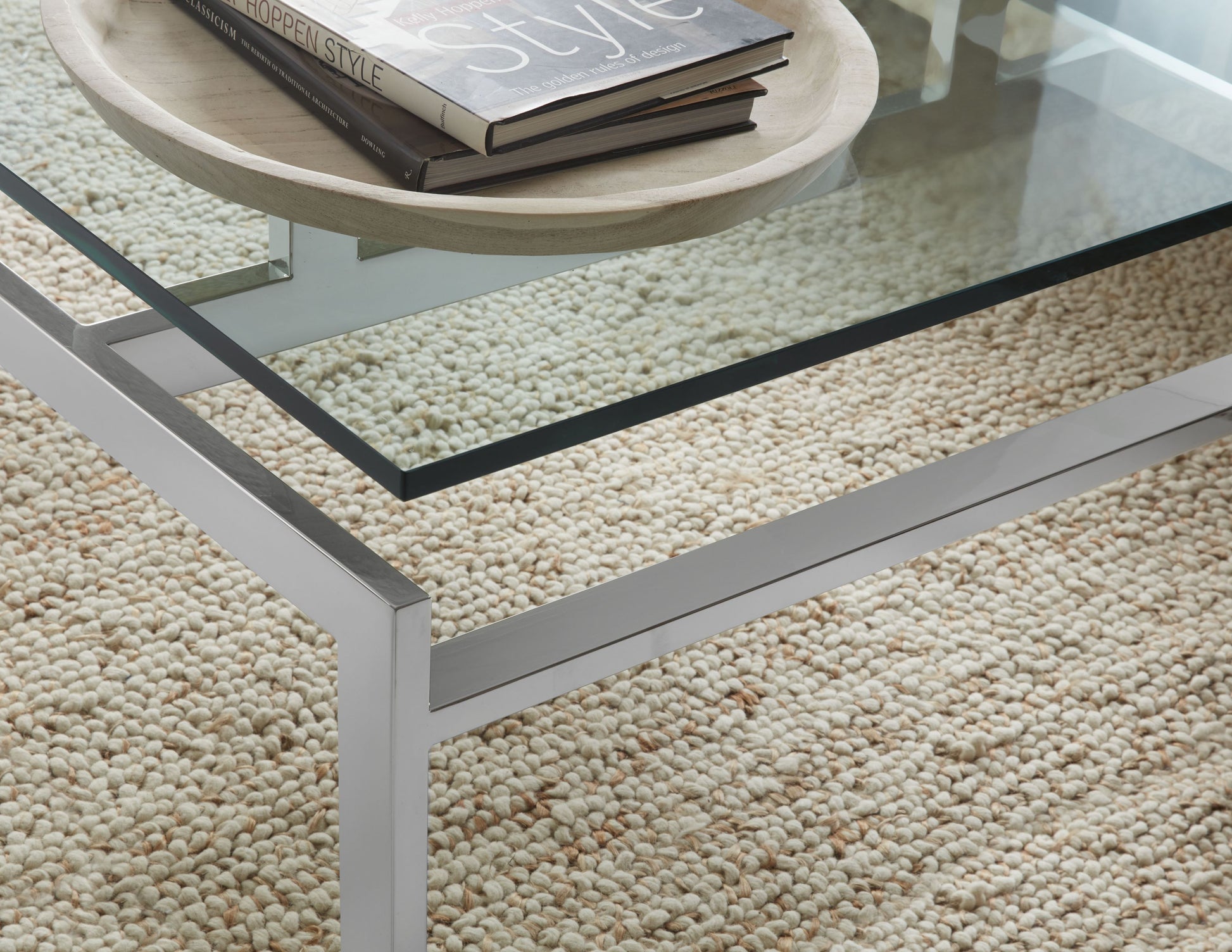 Pictured here, in this detail shot, "The Lance" Cocktail Table is a quintessentially modern piece that encompesses simplicity and timeless elegance. This rectangular cocktail table features a sleek stainless steel frame paired with a clear glass top, creating a clean and contemporary look that complements any decor style.