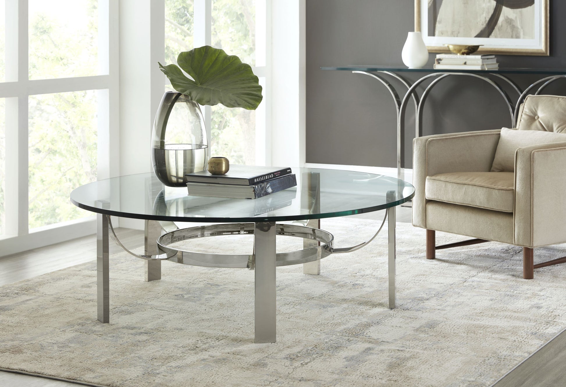 Pictured in this lifestyle shot, The Tahoe Cocktail Table is a perfect embodiment of modern elegance and timeless design, making it a standout piece for any contemporary living room or lounge area.

This quintessentially modern cocktail table features a sleek metal frame with clean, geometric lines that create a minimalist yet striking base. Topped with a round glass tabletop, the Tahoe Cocktail Table offers a versatile surface that adds an airy and sophisticated touch to any decor.