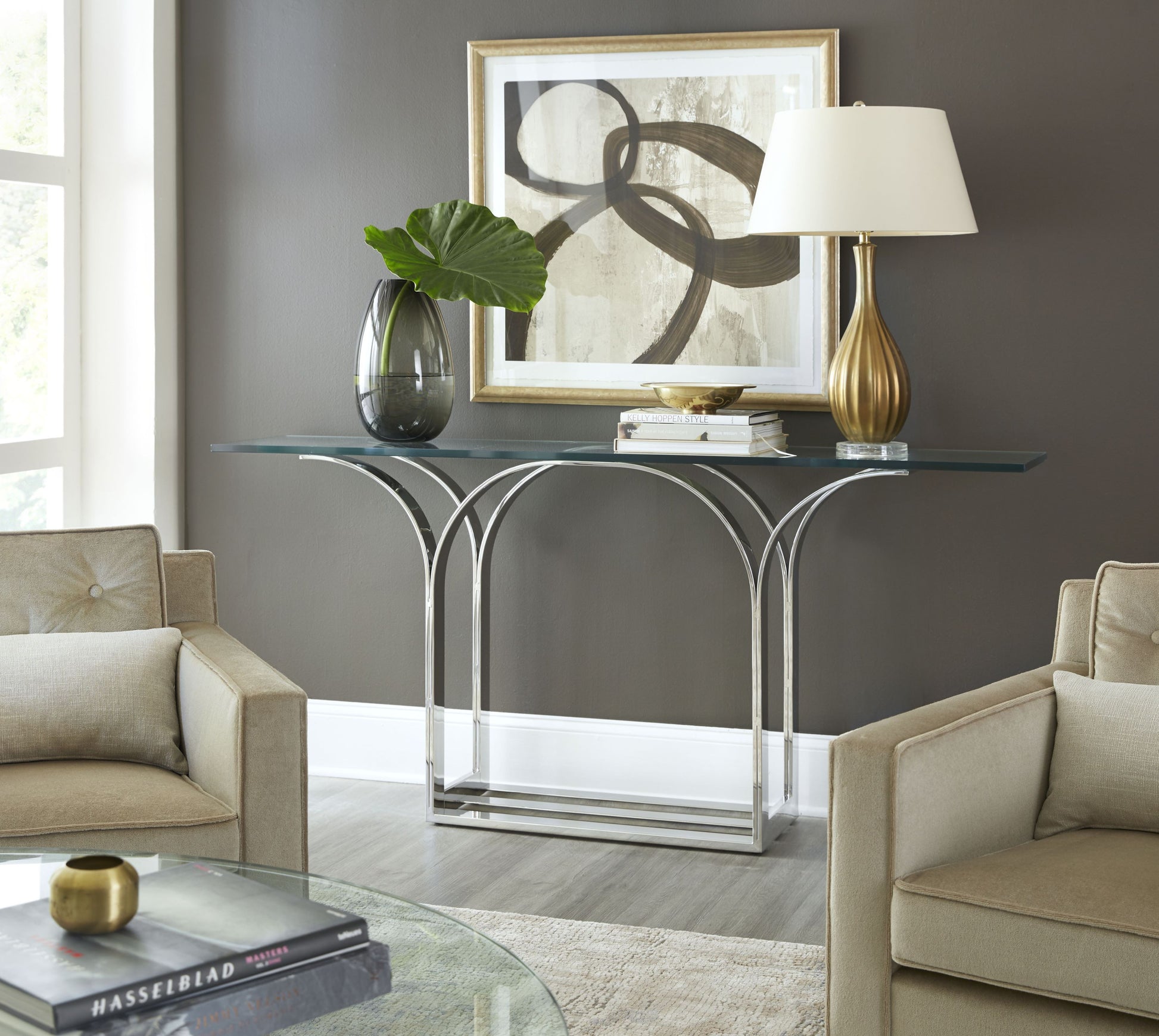 Pictured here in this lifestyle shot, The Trellis Console Table is a sleek and sophisticated addition to any lounge area or living room. Featuring a sturdy stainless steel base and a clear glass tabletop, this console table embodies a modern aesthetic with its clean lines and minimalist form.

Inspired by the intricate geometric patterns of a classic trellis design, the table’s base showcases an elegant interplay of lines and angles, creating a visually striking effect.